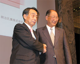 経営統合を発表し、握手する明治製菓佐藤社長（左）と明治乳業浅野社長