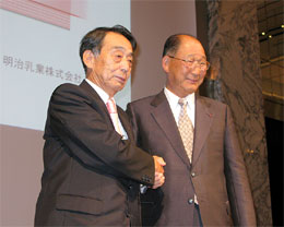 経営統合を発表し、握手する明治製菓佐藤社長(左)と明治乳業浅野社長
