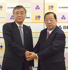 がっちりと握手する児玉氏(右)と山本氏
