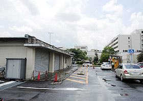 現在は車庫（左）が設置されている外来患者用駐車場の一角に、3階建ての施設が新設される