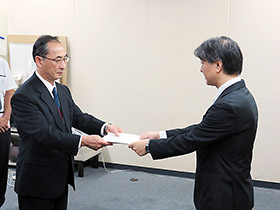 伊澤監視指導・麻薬対策課長(右)が処分通知を木下理事に手渡した
