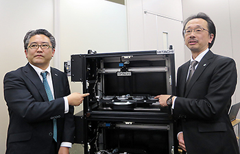 自動解析装置とヒロツバイオ代表取締役の広津崇亮氏(左)、日立製作所・基礎研究センタ主任研究員の久野範人氏