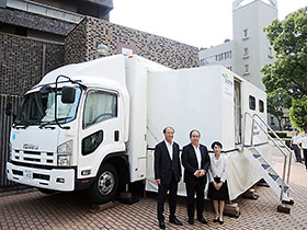 無償で貸し出されるデモ車と、提携した3者の代表者(中央=兵庫県薬・笠井秀一会長)