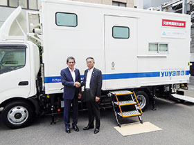 災害時調剤支援車の前で握手を交わす大阪府薬剤師会・藤垣哲彦会長(右)とユヤマ・湯山裕之会長
