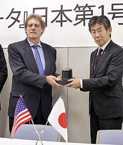 ゲラマン博士(左)から日本第1号機を受け取るキリン堂の寺西社長