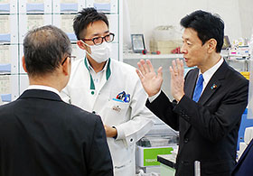 視察する西村康稔大臣(右)