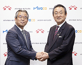 握手するみらかホールディングス・竹内成和社長(左)とメディパルホールディングス・渡辺秀一社長