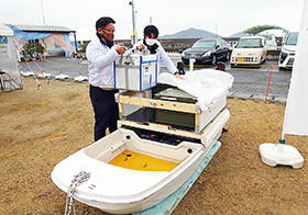 調剤薬を入れた保冷箱を無人小型船に積み込む模擬作業