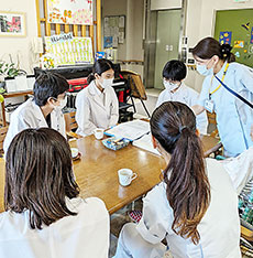 実習を受ける2人の薬学生（奥中央）＝広島大学提供