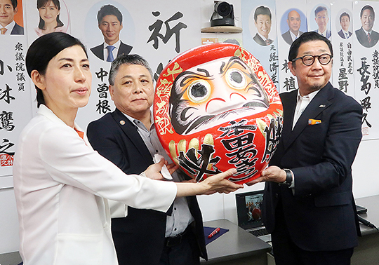 再選を果たし、だるまの目入れを行った本田氏(左)