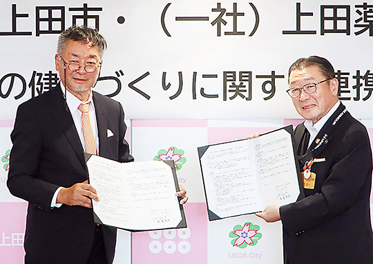 協定書に署名した飯島会長(左)と土屋市長