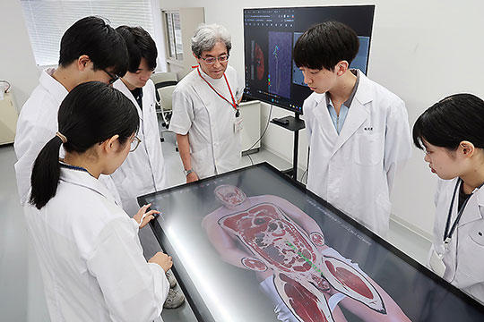 バーチャル解剖台では人体の構造を3Dで視覚的に理解できる。右から3番目が加納教授