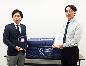 「PATTHERMO」を持つPCM事業化チームリーダーの三平淳也氏（左）、カネカフォームプラスチックスPCM営業部東京営業課の岩下修介氏