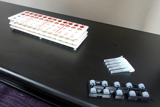 3Dプリンターで制作した試験管ラック(左)や注射針保持ホルダー(右)、ゴム栓ホルダー(下)