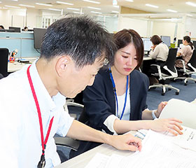 書類の解釈について上司に相談をする大宮さん（右）