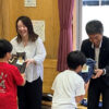 子どもたちに手渡しする井上東北支社長（右）と業務課の岩渕さん